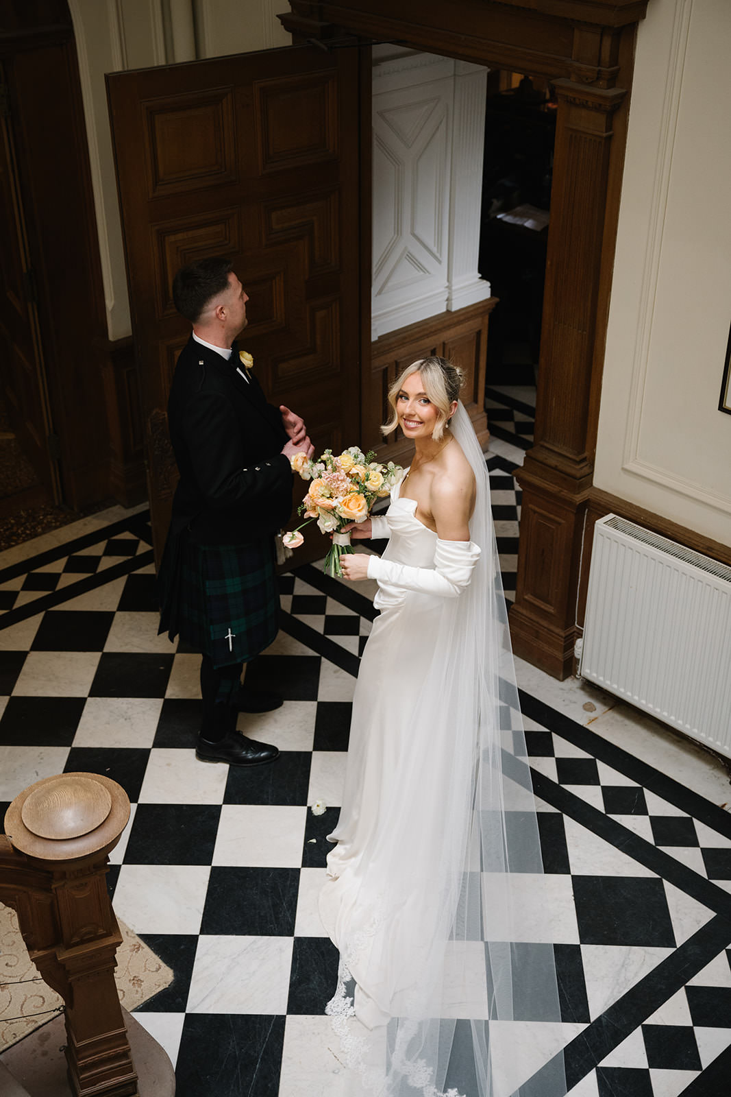 Hannah and John at the bottom of the stairs at Springkell House wedding.
