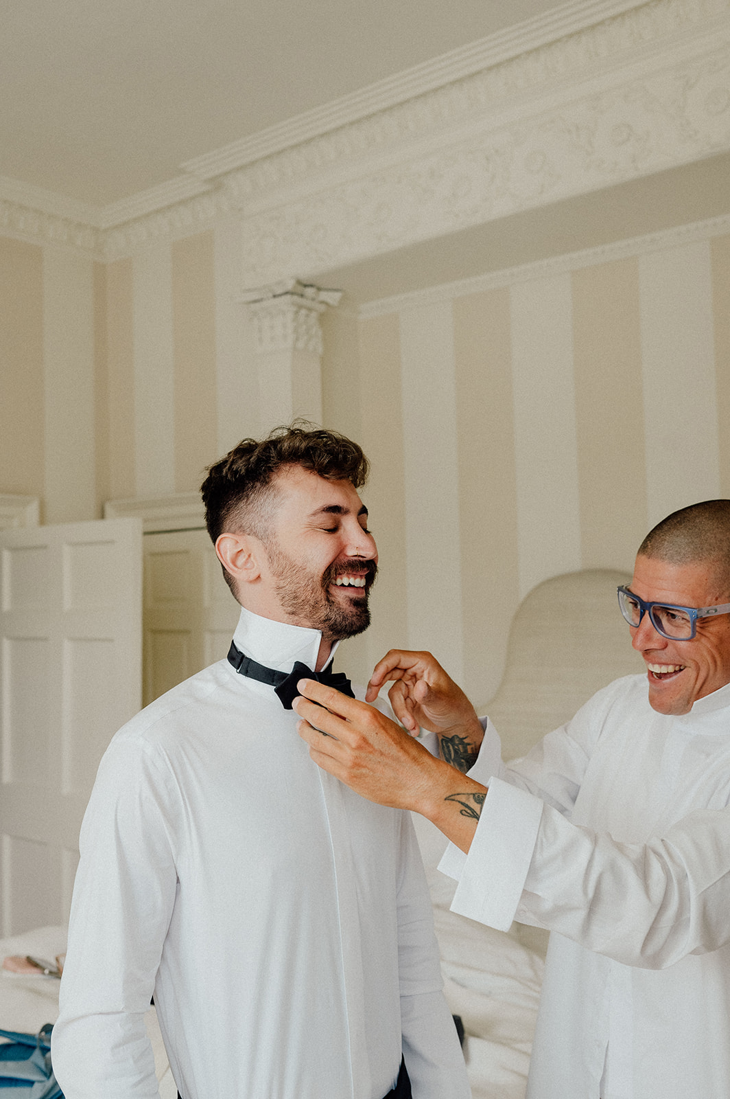 Grooms brother in law helps him putting on the bow.