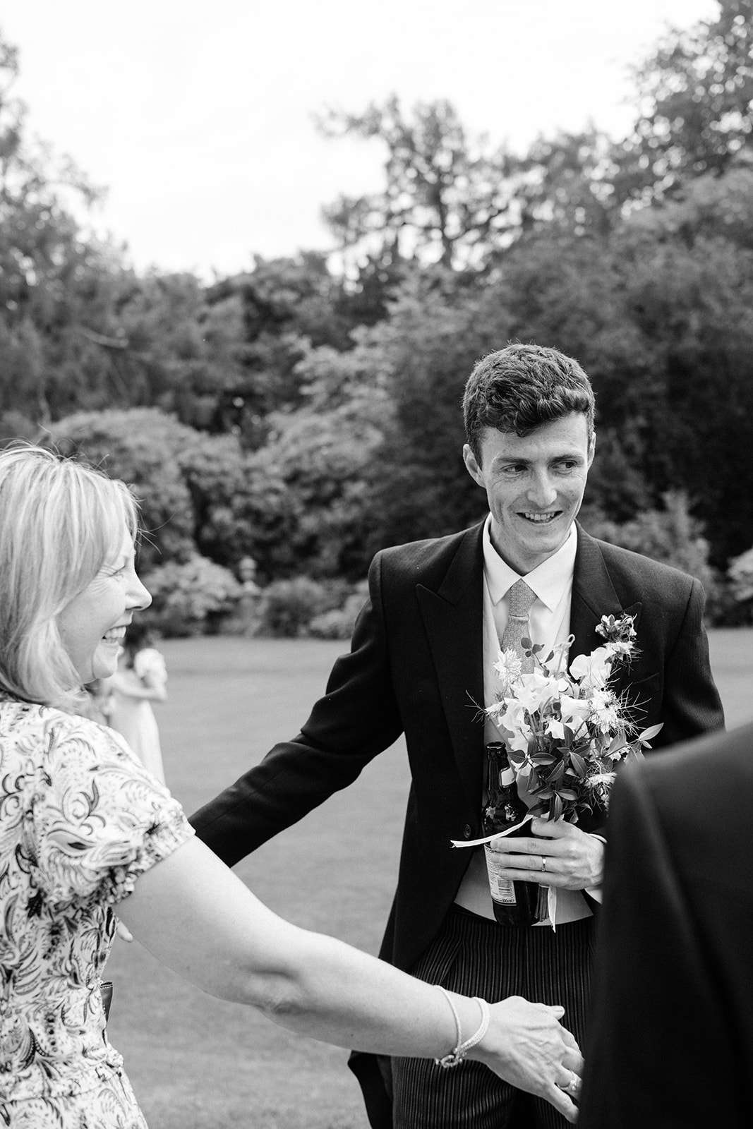 Black and white photo of the groom holding the flowers.
