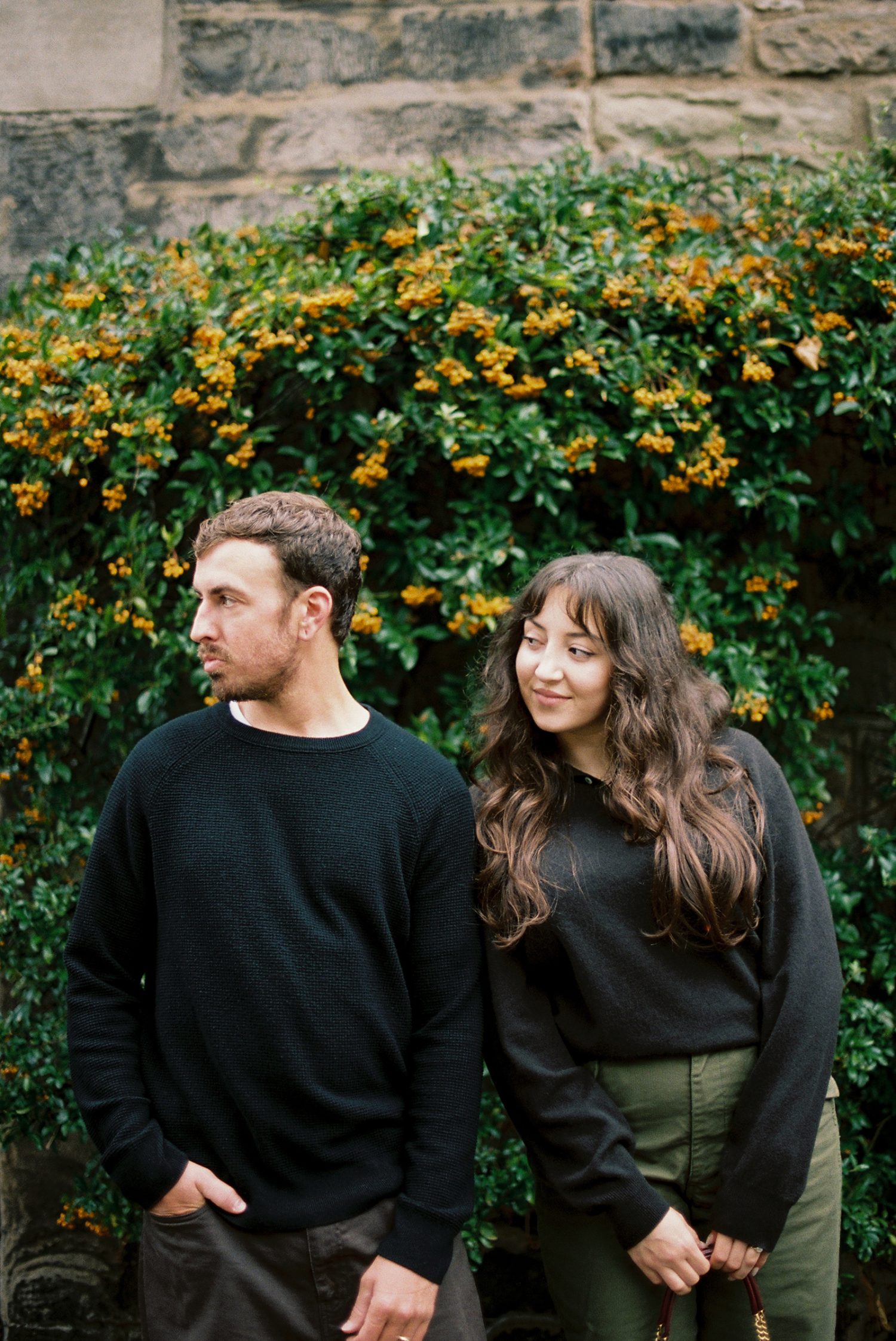 Close up 35mm film shot of Sara holding Brandon’s hand in autumn light - analogue photographers in Scotland.
