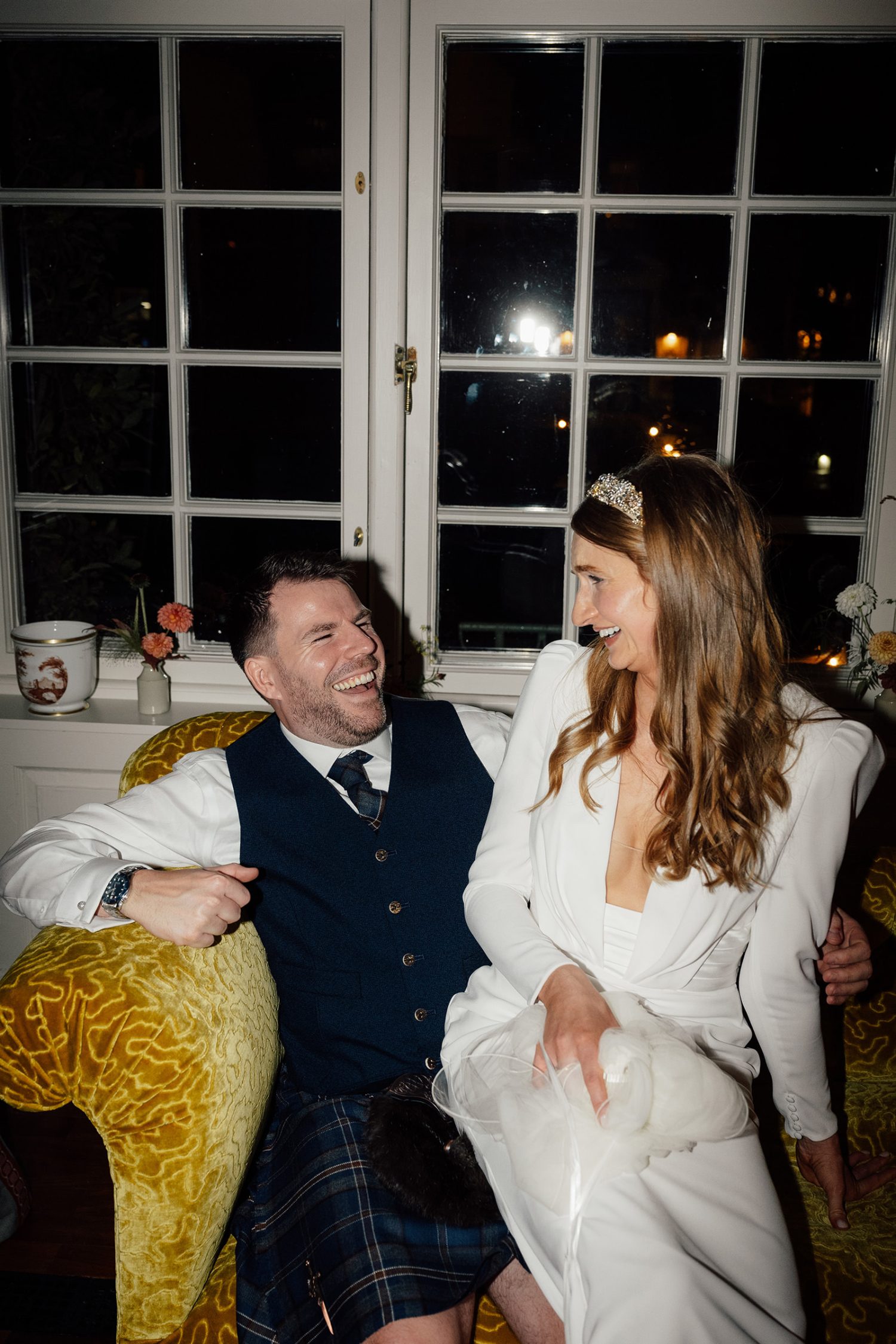 Wedding couple sitting on a sofa just before their evening reception.