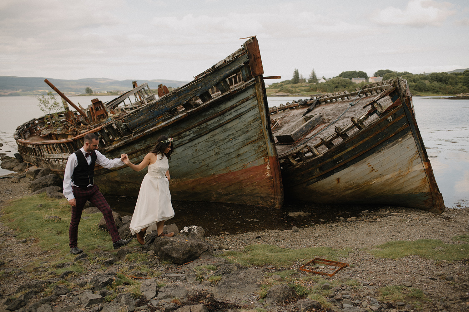 Wedding couple posing for elopement photos with a shipwreck.